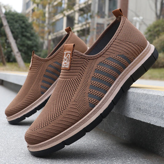 Brown slip-on shoes with a visible brand logo on a concrete surface.