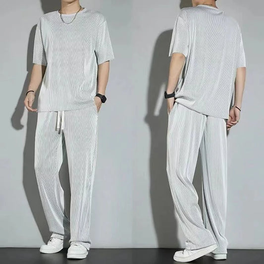 Person wearing a light gray outfit with a t-shirt and pants, standing against a plain background.