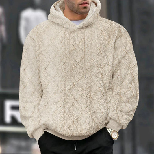 Person wearing a beige cable knit hoodie with a blurred background