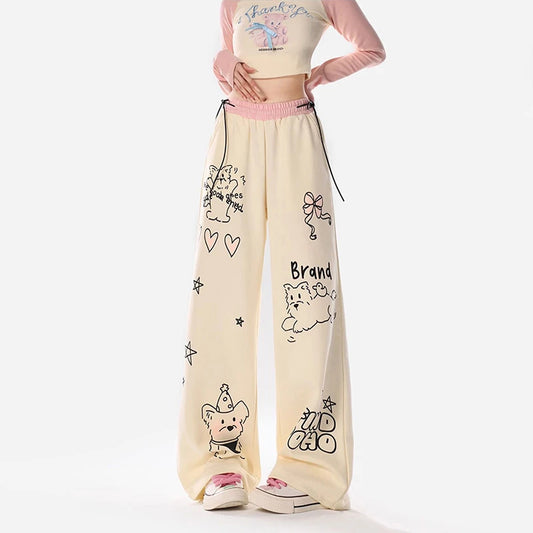 Beige pants with cartoon designs worn by a person on a white background