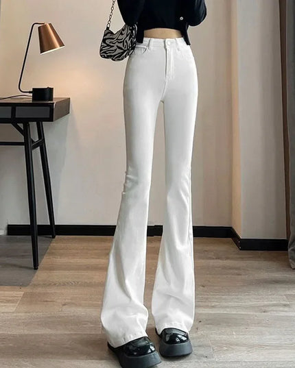 Person wearing white flared jeans in a room with a desk and lamp.