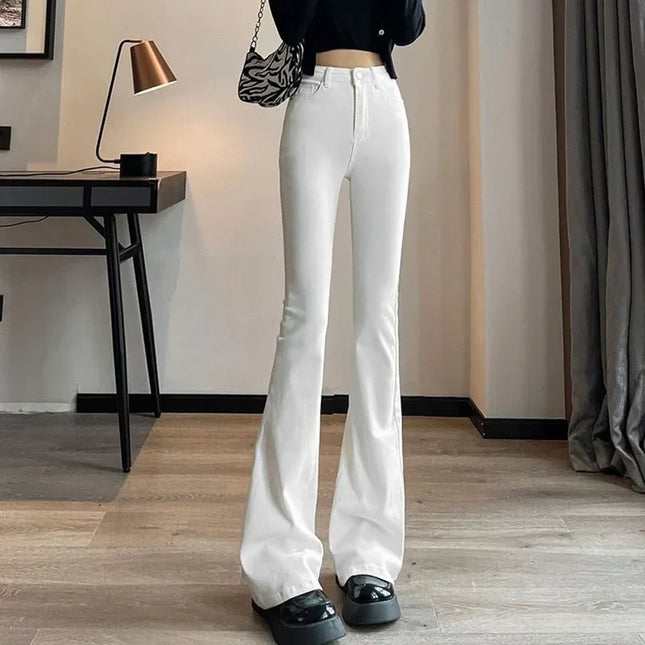 Person wearing white flared jeans in a room with a desk and lamp.