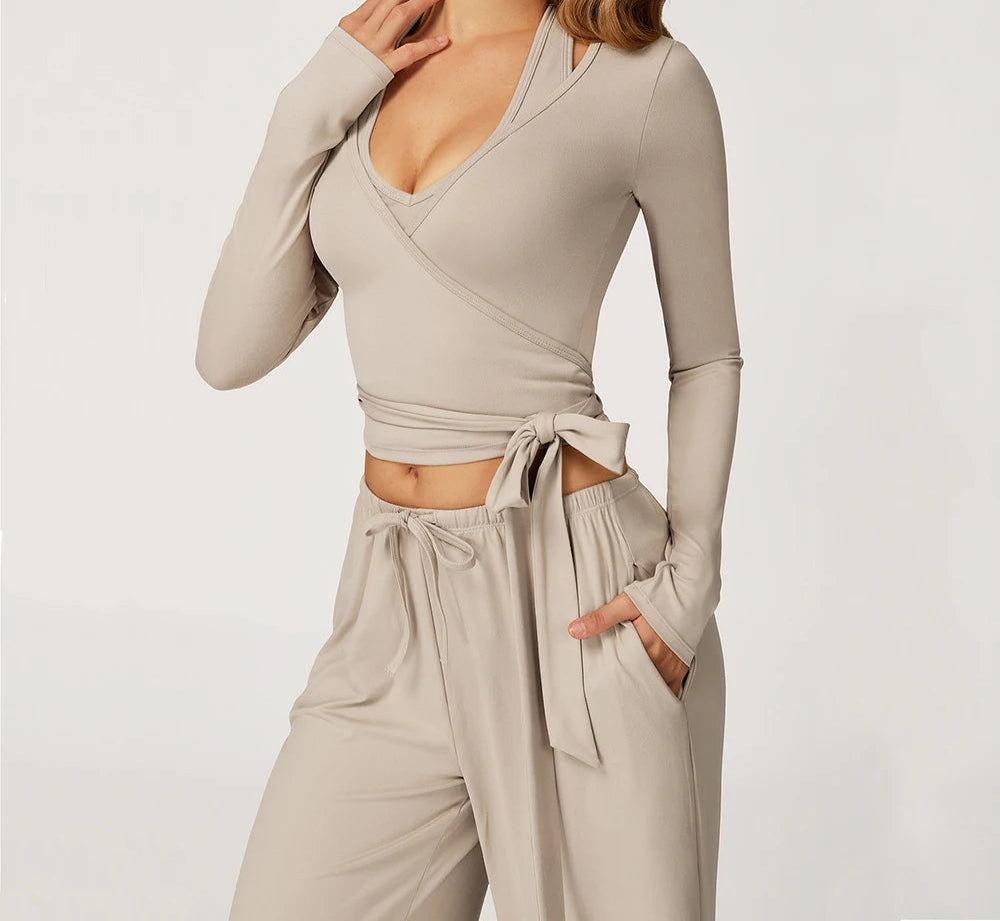 Woman wearing a beige long-sleeve top and pants with 'SWELTERING' branding.