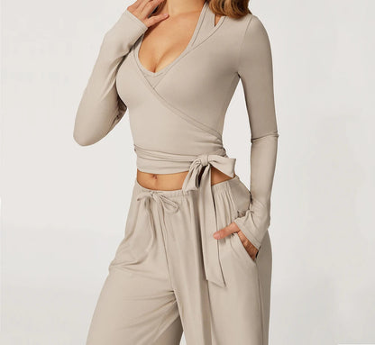 Woman wearing a beige long-sleeve top and pants with 'SWELTERING' branding.