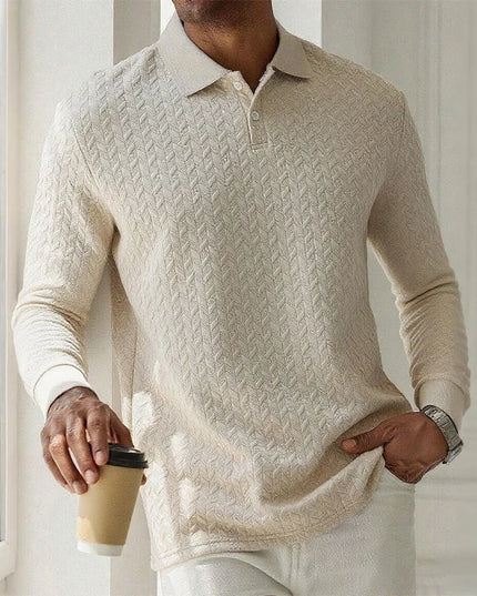 Person wearing a beige cable knit sweater holding a coffee cup indoors.
