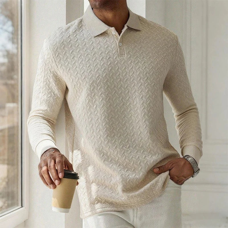 Person wearing a beige cable knit sweater holding a coffee cup indoors.