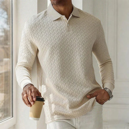 Person wearing a beige cable knit sweater holding a coffee cup indoors.