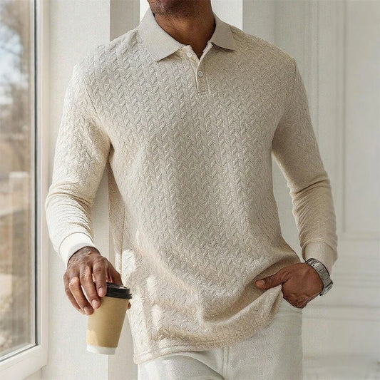 Person wearing a beige cable knit sweater holding a coffee cup indoors.