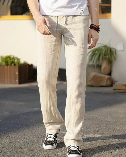Person wearing beige pants and black sneakers standing outdoors.