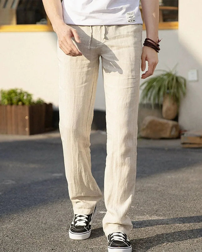 Person wearing beige pants and black sneakers standing outdoors.