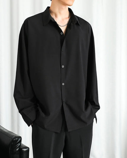 Person wearing a black shirt and pants against a white curtain background