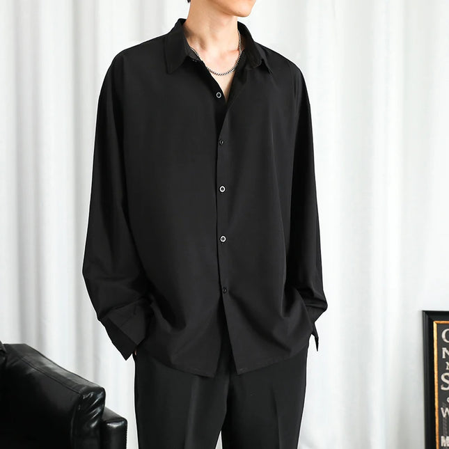 Person wearing a black shirt and pants against a white curtain background