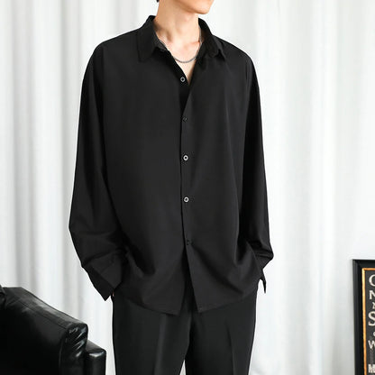 Person wearing a black shirt and pants against a white curtain background