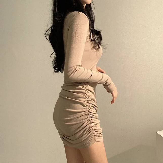 Beige long-sleeve dress worn by a person against a plain background