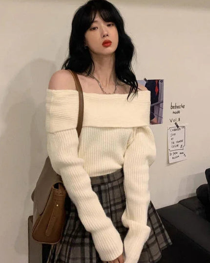 Woman wearing a white off-shoulder sweater and plaid skirt in an indoor setting.