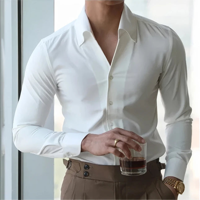 Person wearing a white dress shirt and brown pants holding a glass with a dark liquid.
