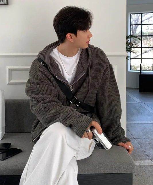 Person sitting on a bench holding a phone, with shopping bags in the background