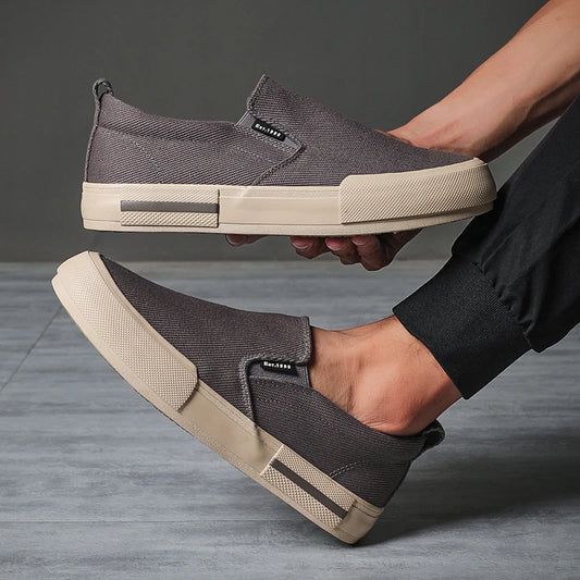 Person holding a gray slip-on shoe with beige sole on a gray background