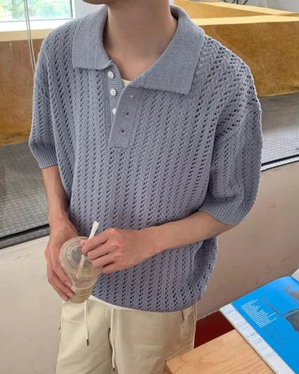 Person wearing a textured gray sweater holding a drink in an indoor setting