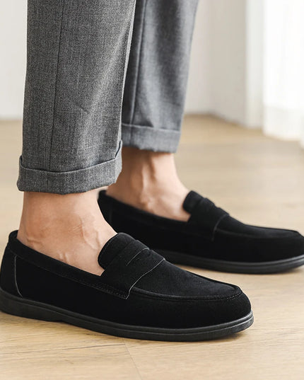 Person wearing black loafers on a wooden floor