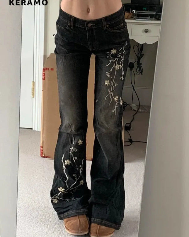 Person wearing black jeans with floral embroidery in a room.
