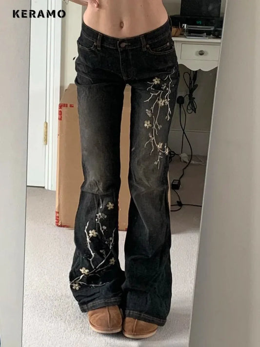 Person wearing black jeans with floral embroidery in a room.