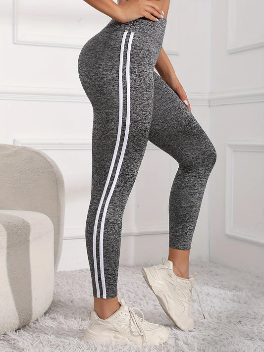 Gray leggings with white stripes worn by a person in a minimalistic room.