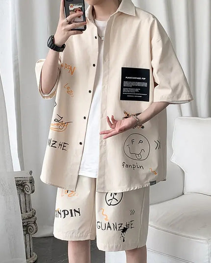 Person wearing a beige shirt and shorts with text and graphics, standing against a white curtain.