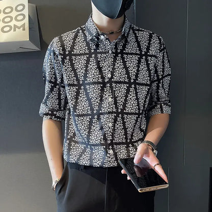 Person wearing a patterned shirt holding a phone against a dark background