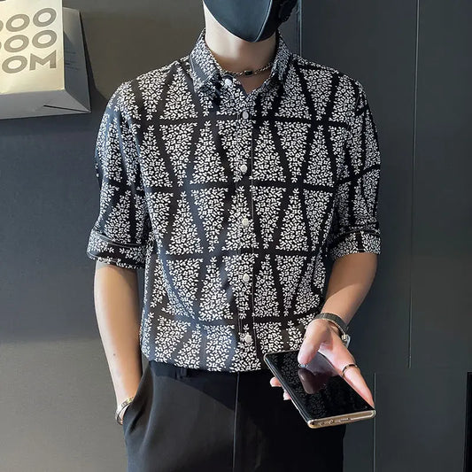 Person wearing a patterned shirt holding a phone against a dark background