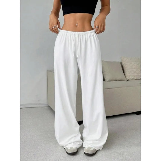 Person wearing white wide-leg pants in a room with a sofa.