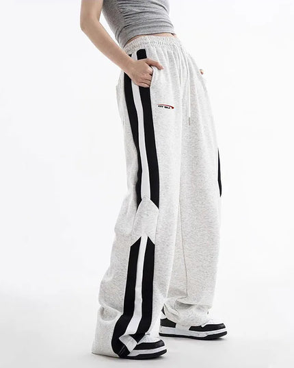 White sweatpants with black stripes worn by a person on a white background