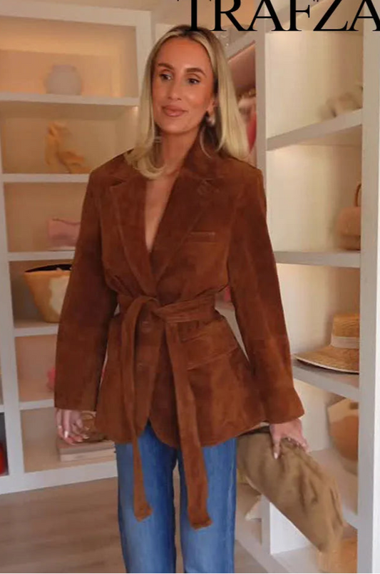 Woman wearing a brown suede jacket in a store setting with 'Trafza' branding.